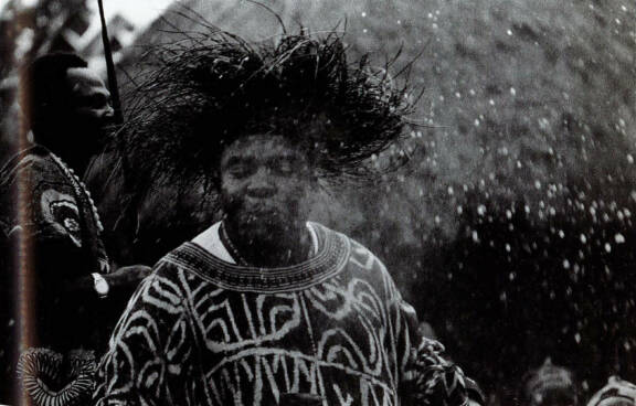 Le roi Ngwa’fo pulvérise du vin de raphia sur la foule et le photographe avec sa bouche. Cameroun, Mankon, décembre 1972. © Jean-Pierre Warnier