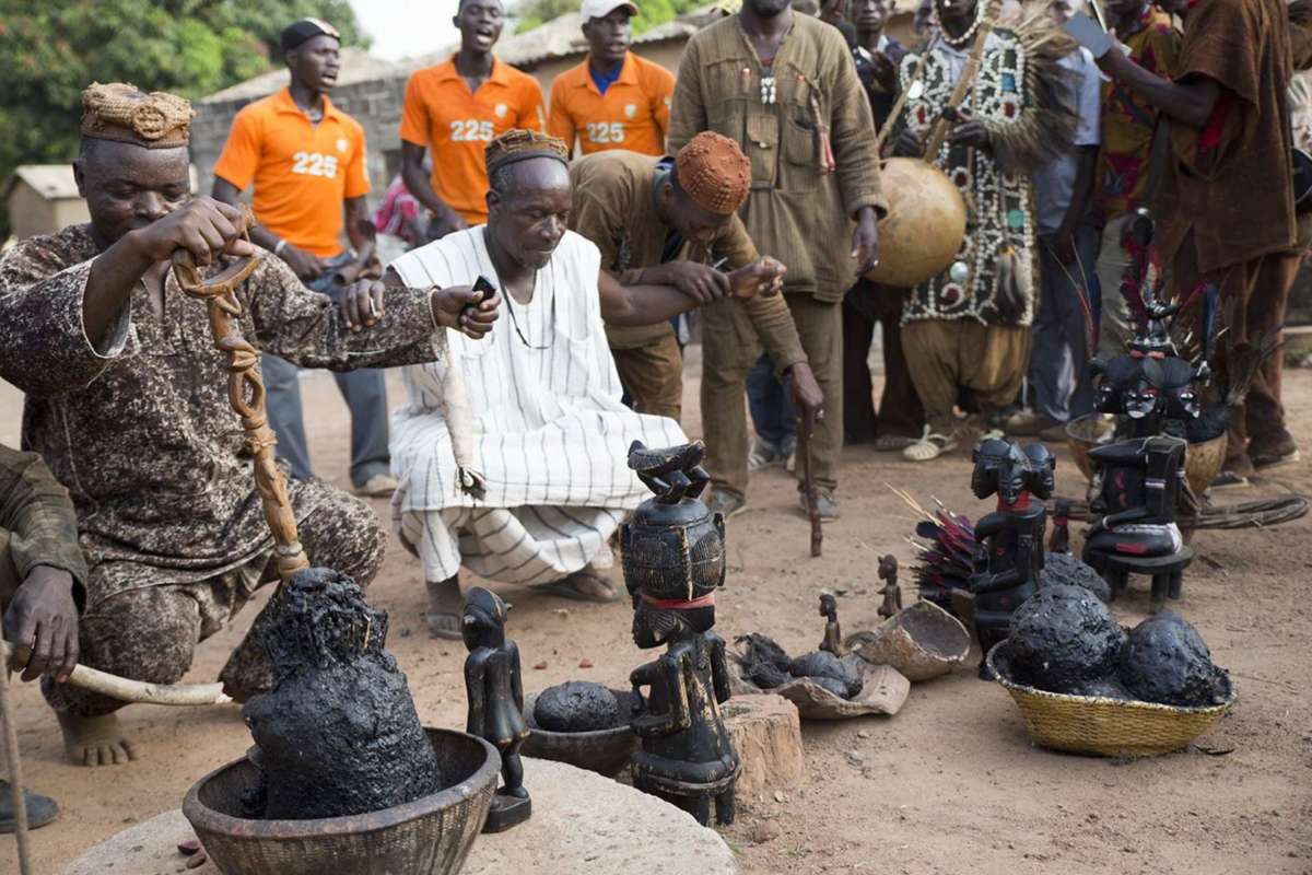 A healer and representatives of the association of hunters pay tribute to the scrubland spirits, represented by the sculptures lined up before them. Korhogo, Côte d’Ivoire, november 2013. © Photo : T Förster