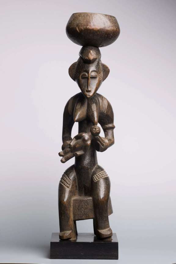 Senufo maternity figure nursing and holding a bowl balanced on her head. © Galerie Simonis